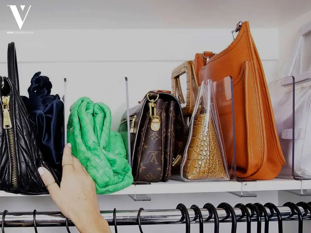 Hand selecting a green woven clutch from a shelf of assorted bags
