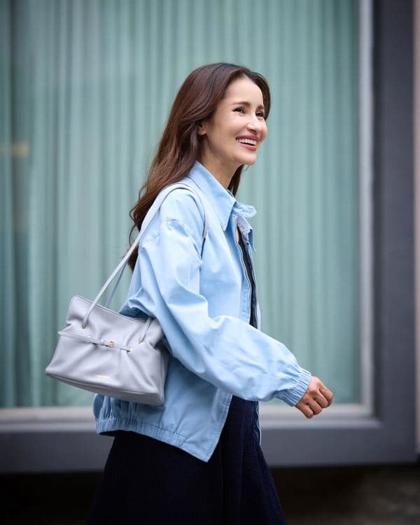 Woman walking outdoors with a pale grey Prada Dada on her shoulder