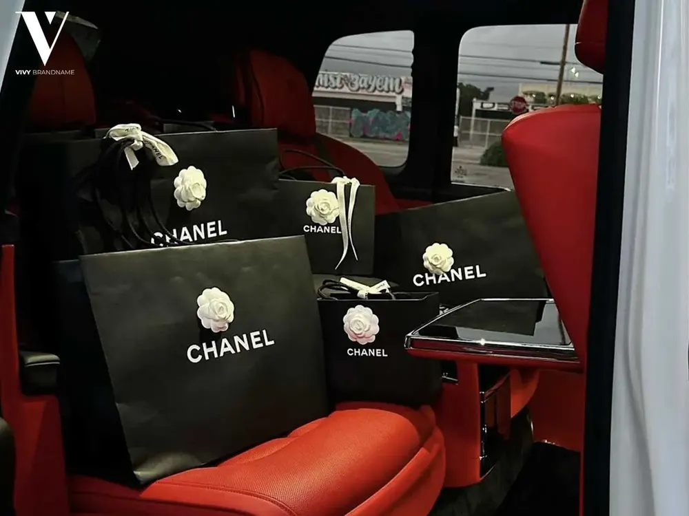 Black Chanel shopping bags arranged on red car seats