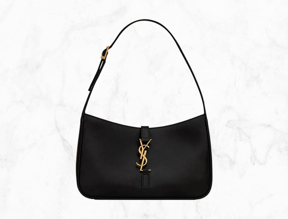 Black glossy-leather Saint Laurent LE 5 À 7 Hobo Bag with gold-tone YSL hardware on a white marble background