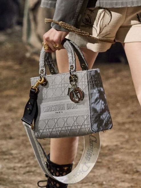 Grey patterned Lady Dior carried by hand with charms and a wide strap
