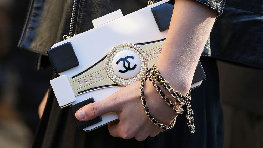 Hand carrying a black-and-white Chanel novelty clutch with chain detail