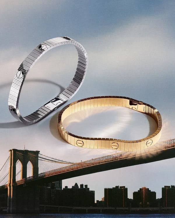 Silver- and gold-toned Cartier Love Unlimited bracelets floating above a bridge skyline