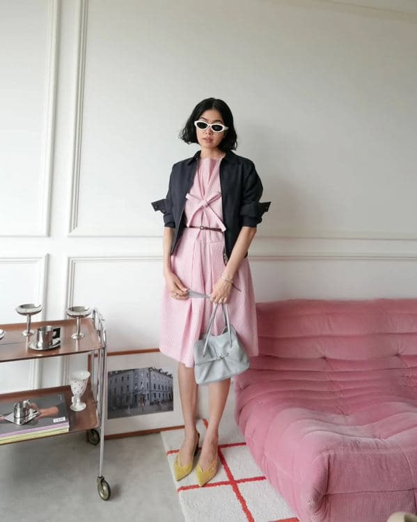 Woman in a pink dress and black blazer carrying a pale blue Prada Dada