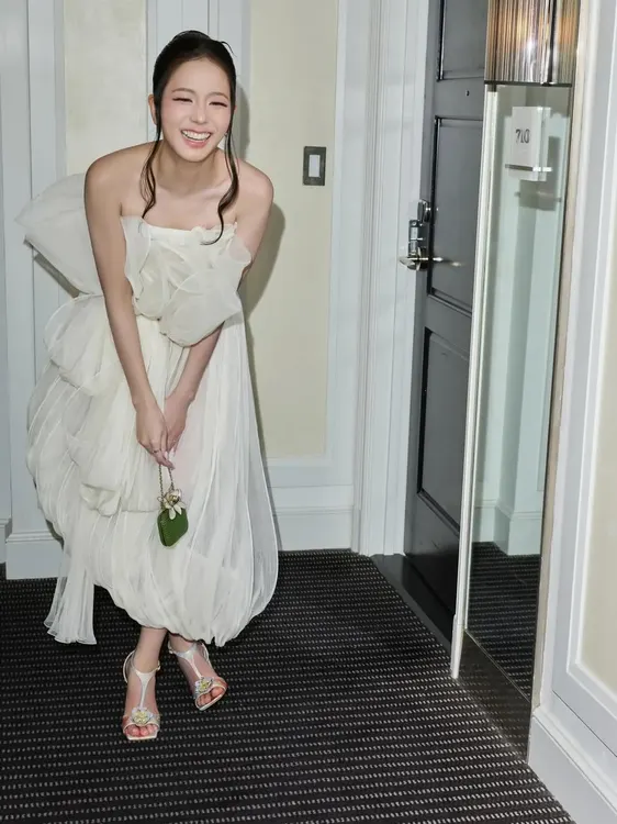 Jisoo walking in a white ruffled dress with the green Dior bag
