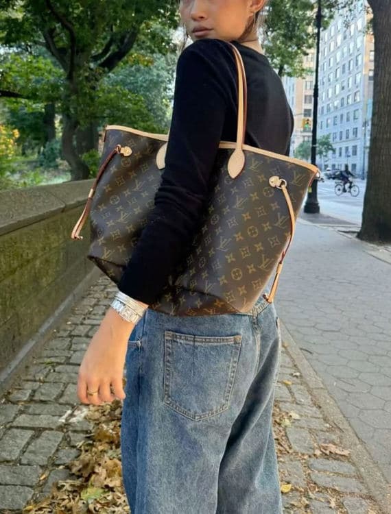 Woman carrying a Louis Vuitton Monogram Neverfull outdoors