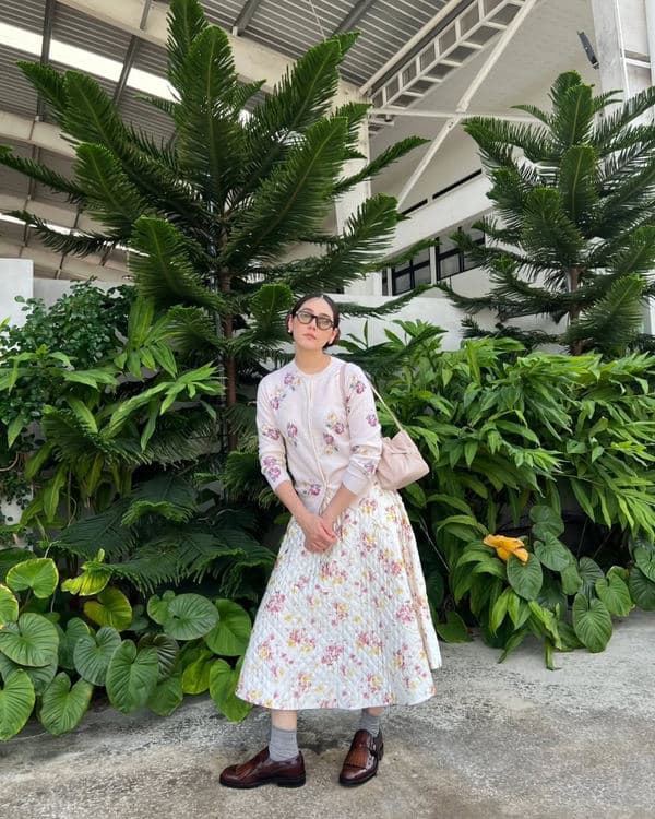 Woman in a floral dress carrying a blush Prada Dada in a garden