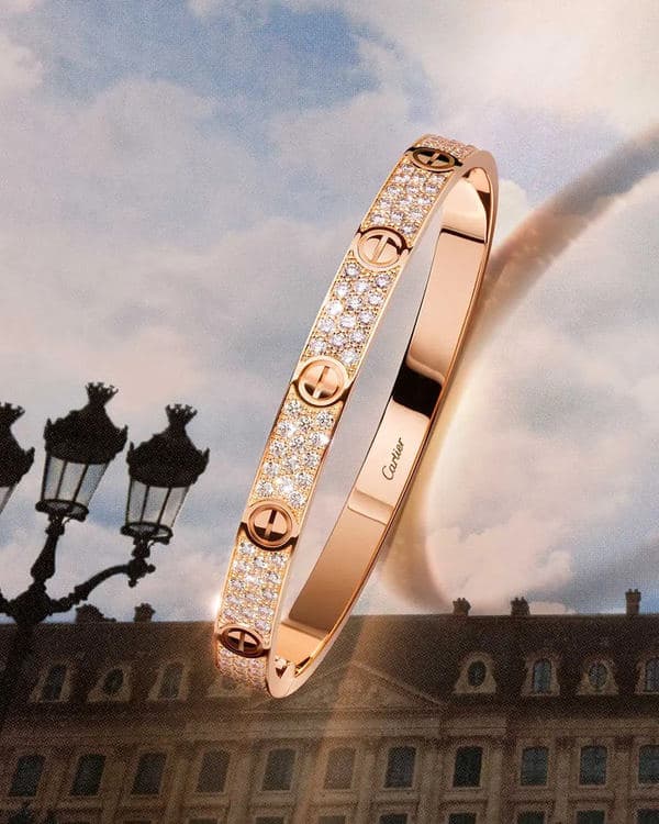 Diamond-set Cartier Love Unlimited bracelet floating above ornate city rooftops