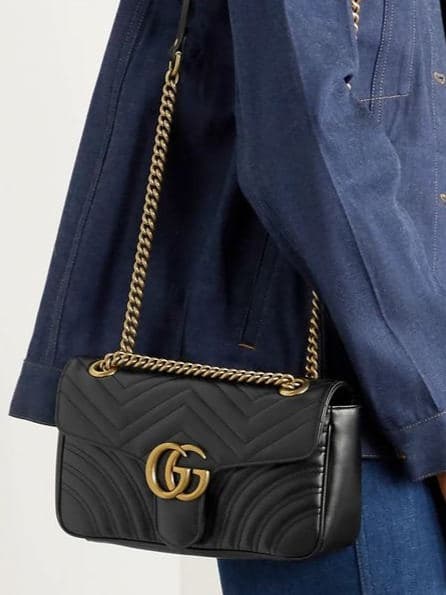 Black quilted Gucci Marmont with gold-tone GG worn on its chain