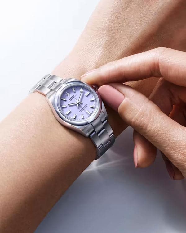 Small steel Rolex Oyster Perpetual watch with a lavender dial on a wrist