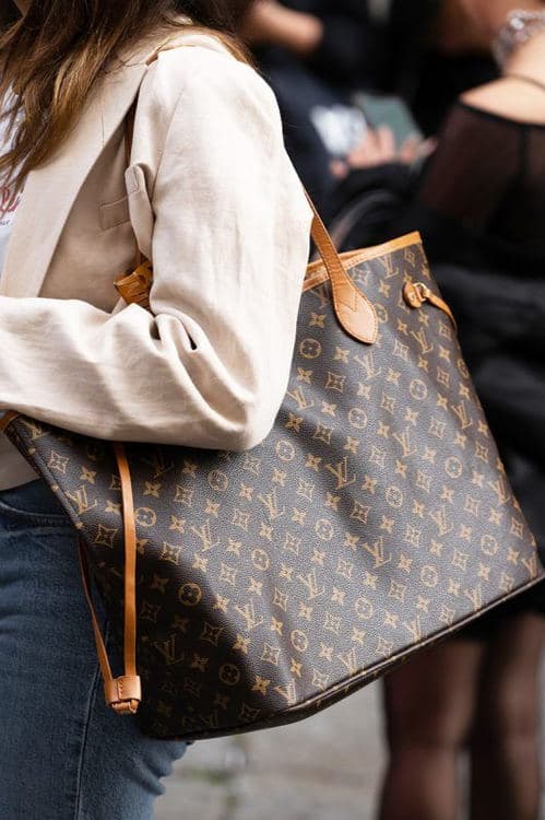 Person carrying an oversized Louis Vuitton Monogram Neverfull on one shoulder