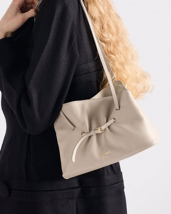 Taupe Prada Dada carried at the side of a model dressed in black