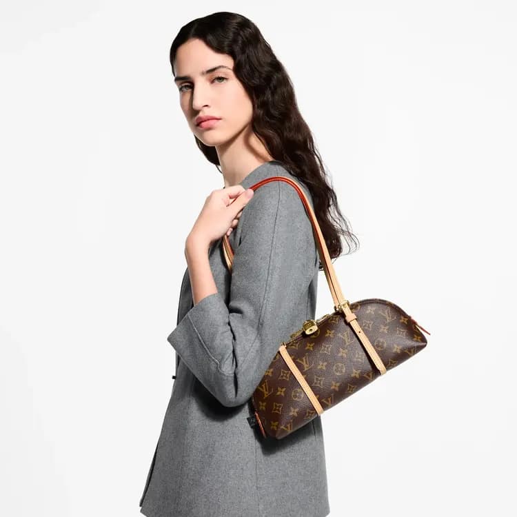 Model shoulder-carrying a brown Louis Vuitton Squire East West bag